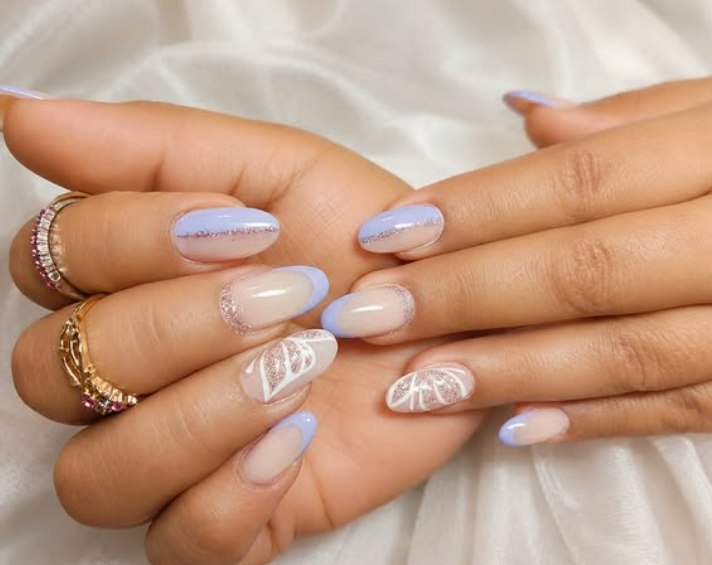 Manos con manicura en tono lila, purpurina y hojas dibujadas en blanco